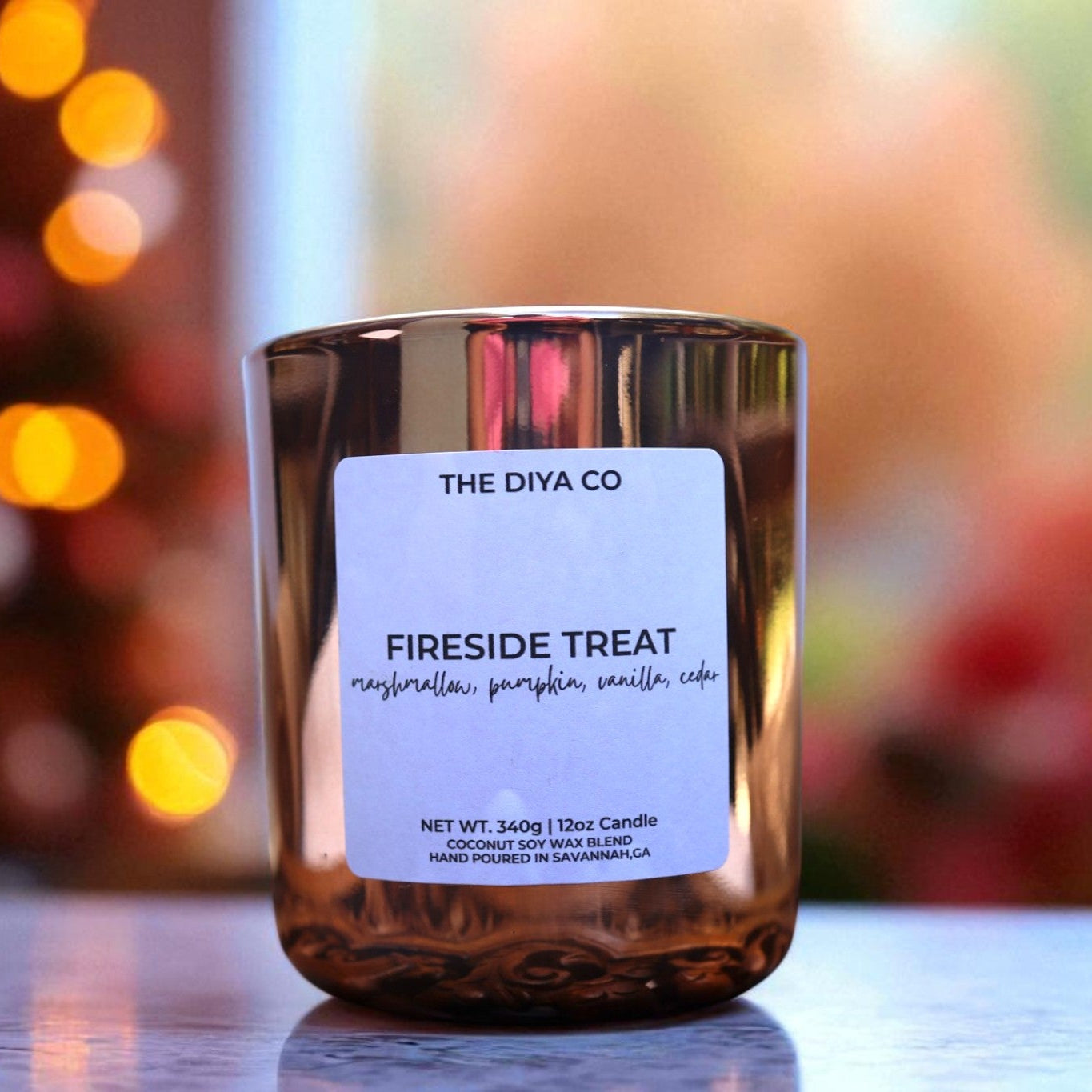 Candle labeled 'The Diva Co Fireside Treat' with a blurred festive background