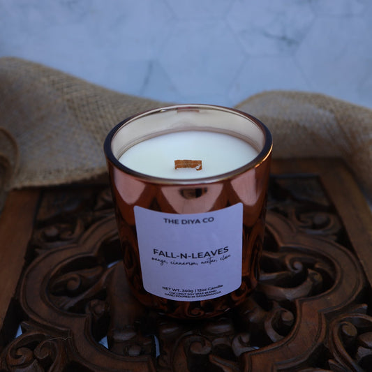 Candle labeled 'Fall N Leaves' from 'The Diya Co' on a decorative wooden tray with burlap in the background.