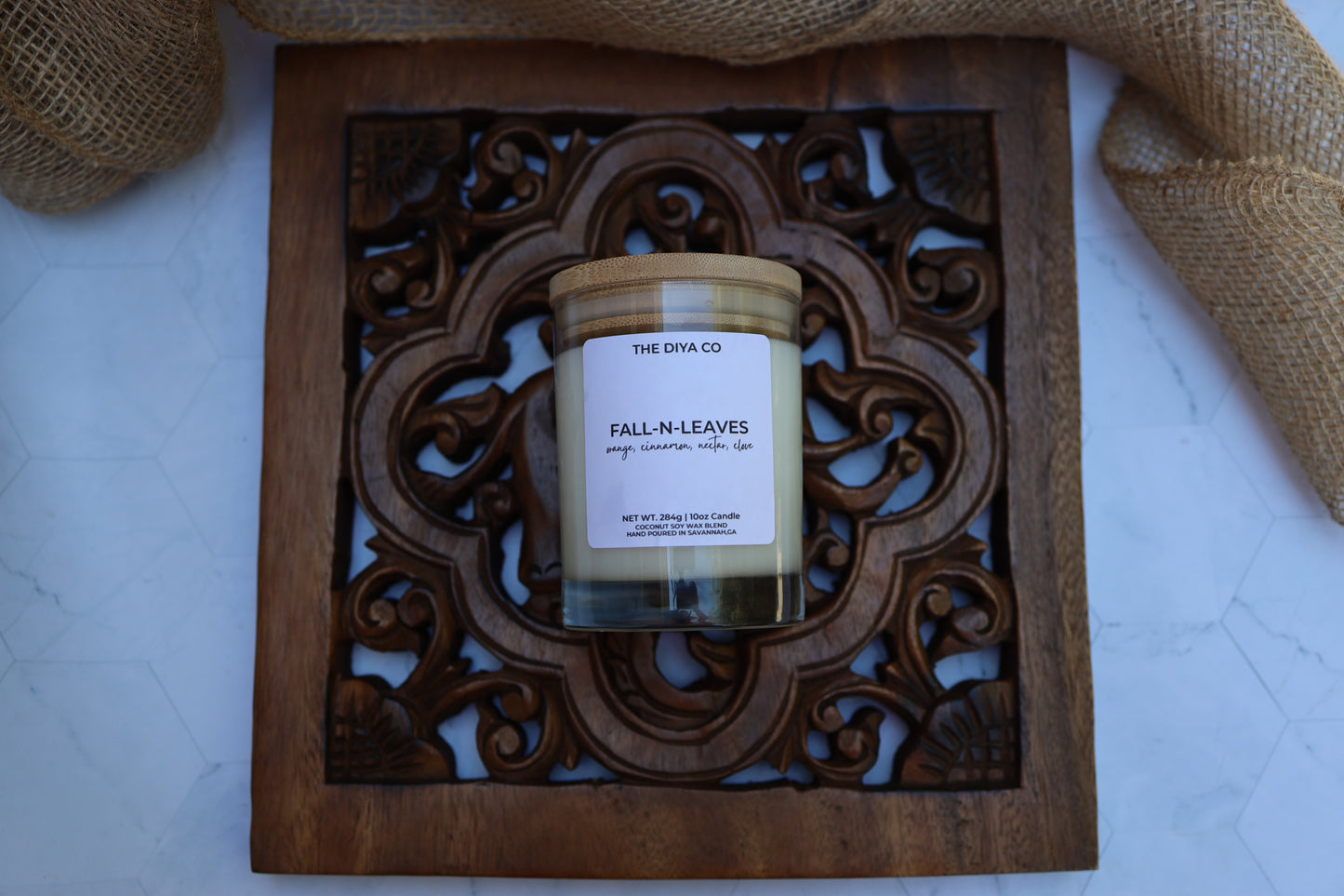Candle labeled 'Fall N Leaves' from 'The Diya Co' on a decorative wooden tray.