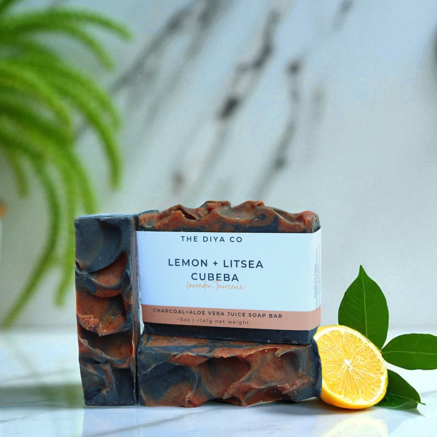 Bar of soap with a label on a marble surface, next to a lemon and green leaves.