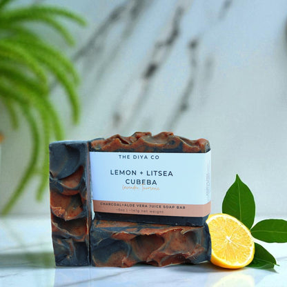 Bar of soap with a label on a marble surface, next to a lemon and green leaves.