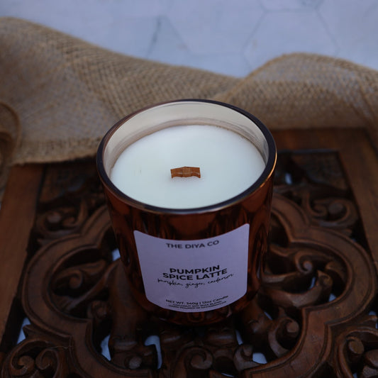 Candle in a decorative jar with a label on a wooden tray, burlap in the background