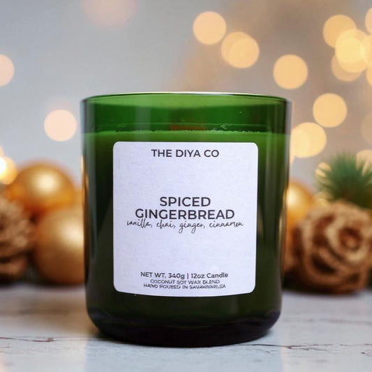 Green candle labeled 'Spiced Gingerbread' from 'The Diya Co.' with festive decorations in the background.